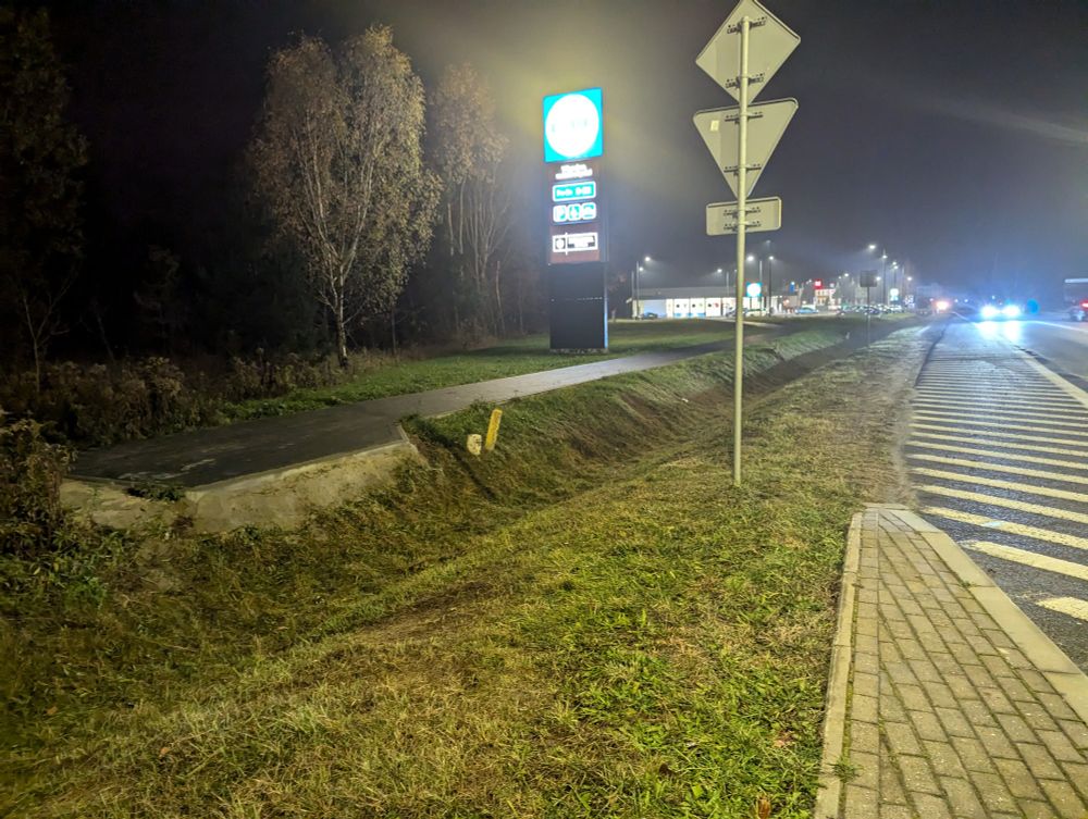 A gap in a sidewalk against blinding lights.