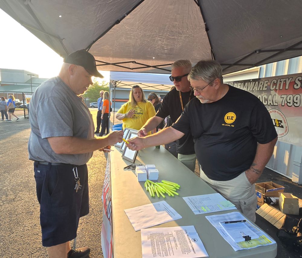 Members hand out pens at the table