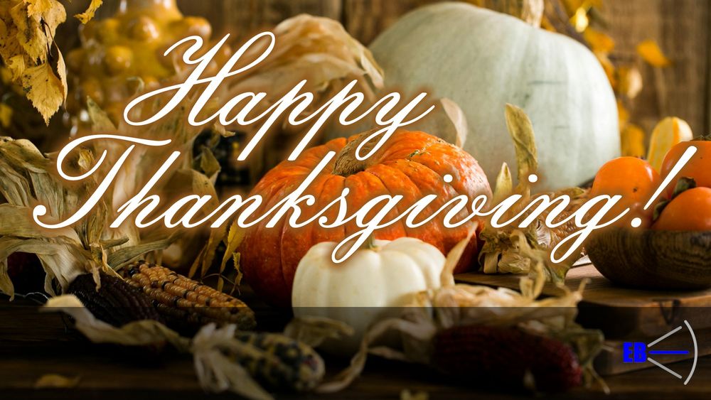 A photo of a variety of pumpkins, corn, and other vegetables and leaves. The words "Happy Thanksgiving" are written in script, and the E. B. Spoke Logo is in the bottom right corner.