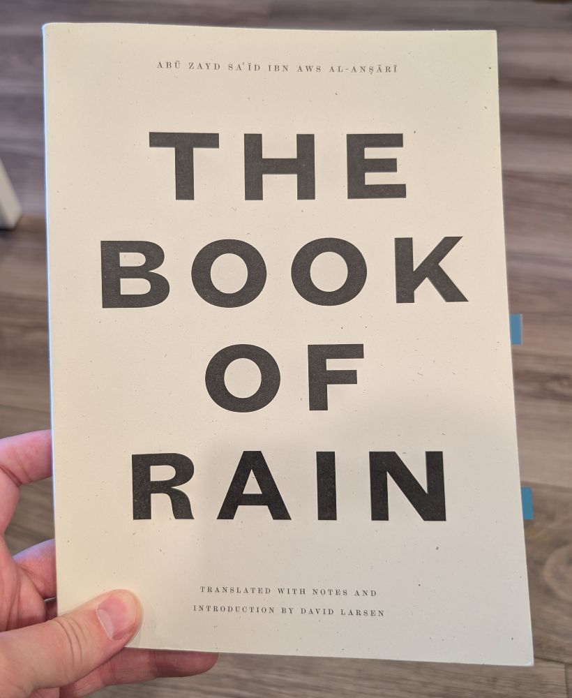 Me holding the Book of Rain by Abu Zaid al-Ansari translated by David Larsen 