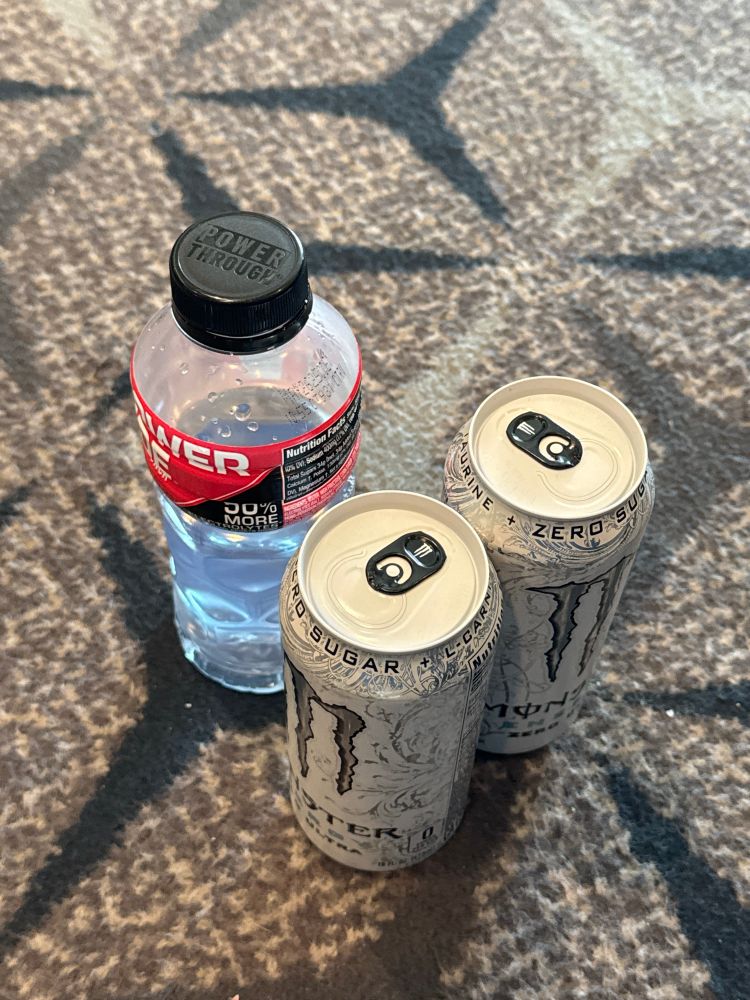 Two cans of Monster energy drinks and a half drunk bottle of Powerade 