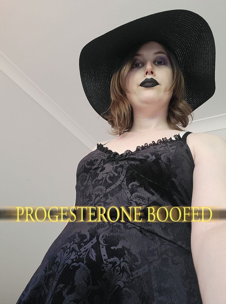 Selfie of Revy in full goth clothing purple eyeshadow and black lipstick and a black aun hat and a black lace dress.
She's staring down like you are a tiny bug.
Text saya progesterone boofed