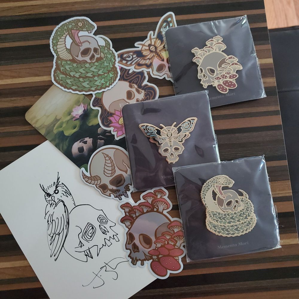 Various skull-themed stickers and pins spread out on a table.