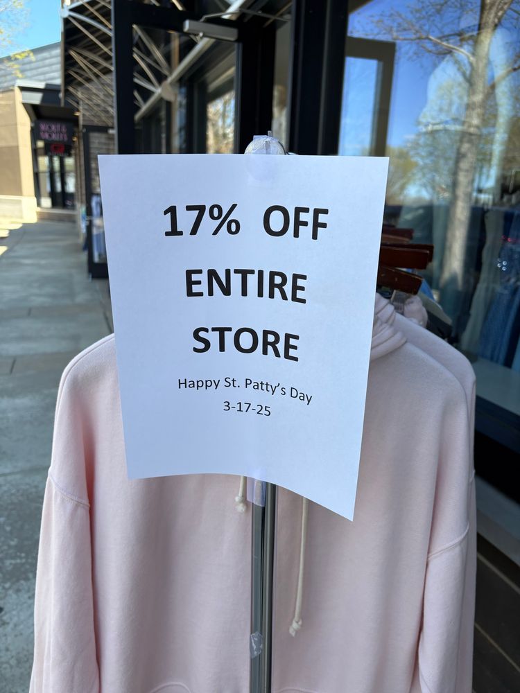 Rack of clothes outside a store with a sign reading “17% off entire store happy St. Patty’s day”