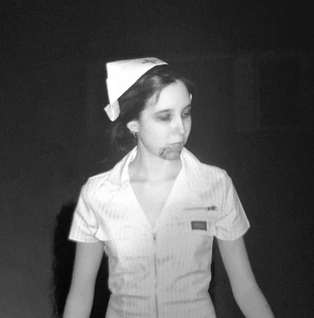 A black and white photo of me on Halloween night in 2006
I'm dressed up as a zombie nurse, in a white dress with a zipper and a nurse cap. My face is turned to the side.