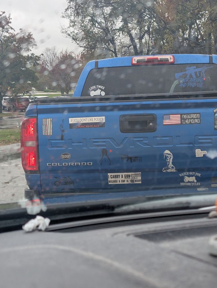 A blue Chevrolet Colorado pickup truck as seen from the rear. The gate is covered in bumper stickers, the most "interesting" of which are described in the next images. 