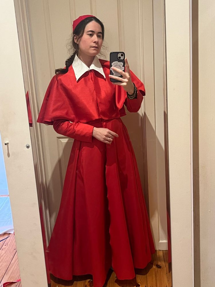 A mirror selfie of an individual wearing a red 17th century cardinal outfit.
