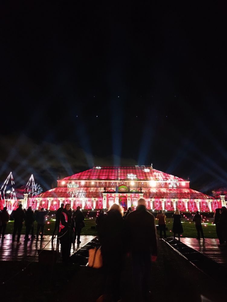 Christmas glasshouse in festive display while spotlights fill the sky.