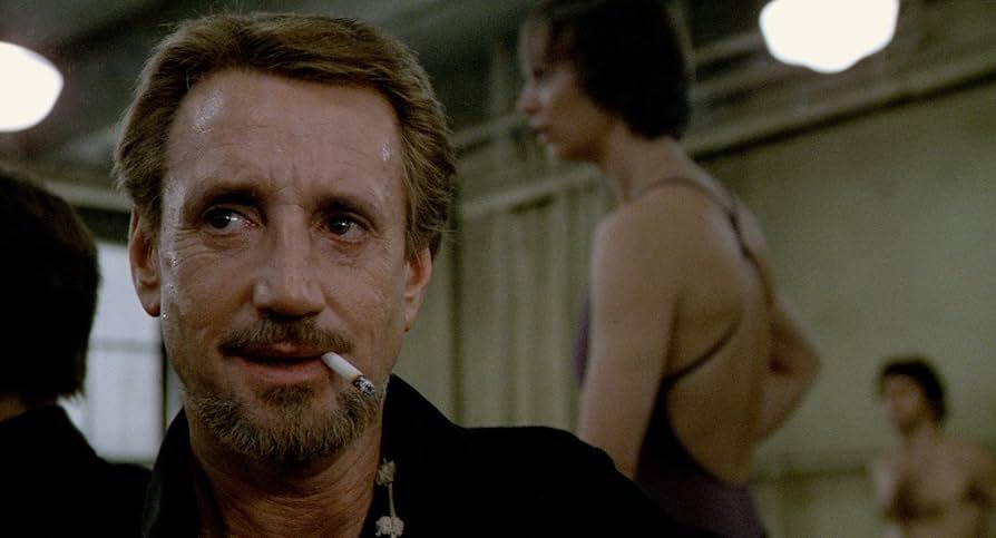 The American actor Roy Scheider sporting a mustache and beard with a cigarette between his lips while portraying American choreographer Bob Fosse in the autobiographical film All That Jazz.