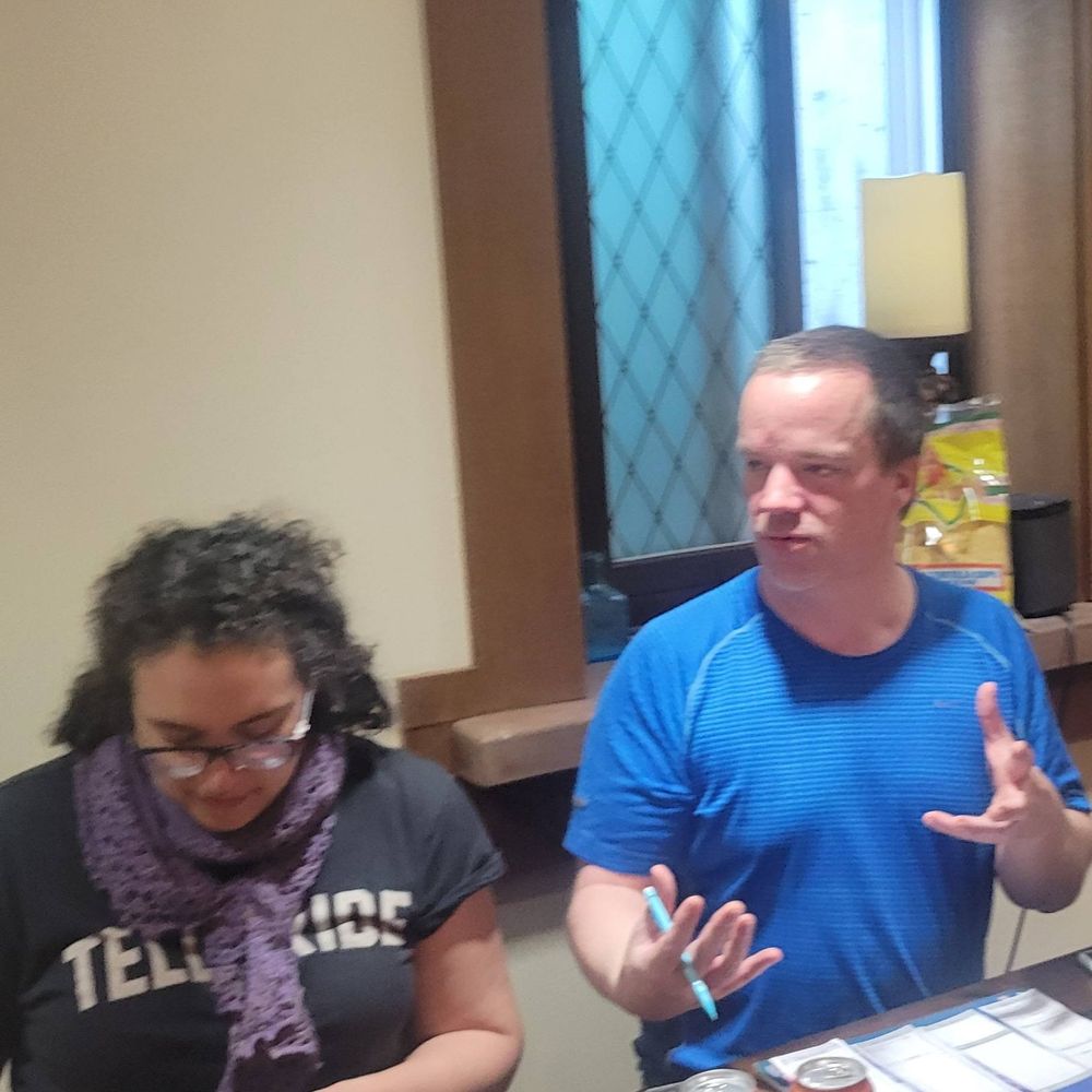 Diana works on her crochet project as Geoff tells the rest of the players at the table about his character's childhood.  