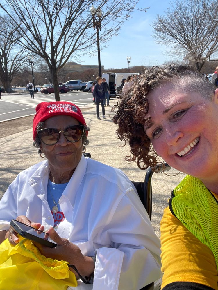 Protester in wheelchair who the the way in the March. Sunburnt March marshal who pushed her chair.