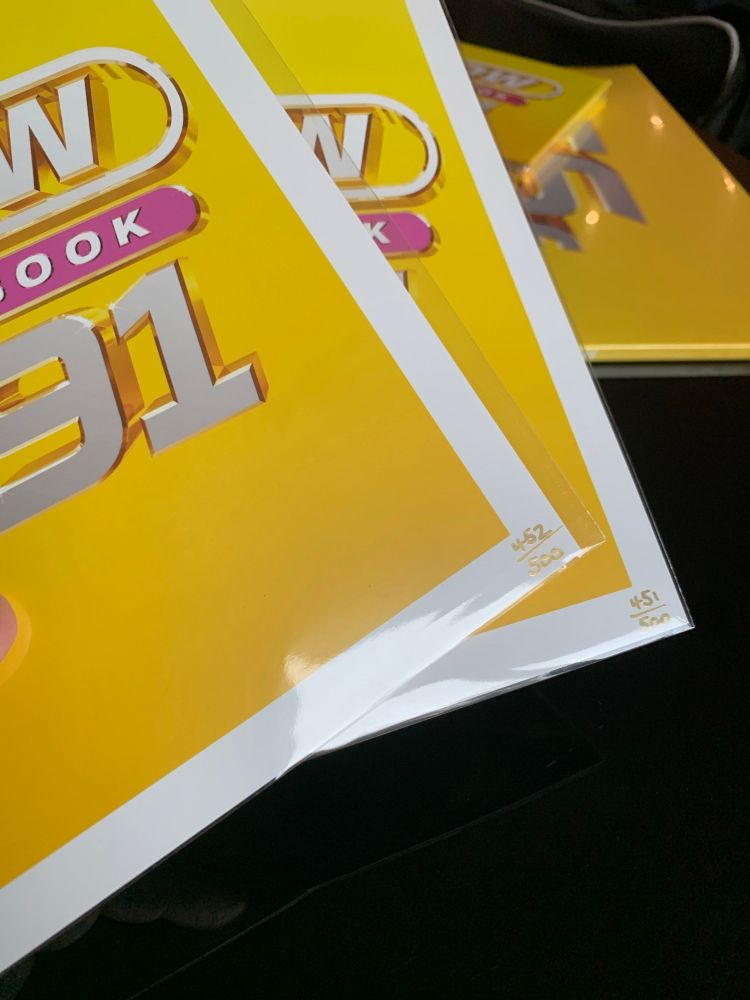 Two glossy yellow art prints from the Now Yearbook 1991 music release, stacked slightly on top of each other. The artwork shows the bold Now Yearbook 1991 logo with a bright yellow background and white border. Handwritten edition numbers appear in the bottom corner, reading 451/500 and 452/500.