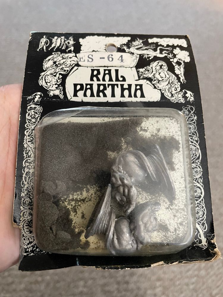 Two Ral Partha metal miniatures—wind/air elementals—in really beat up old packaging with disintegrated foam cushioning.