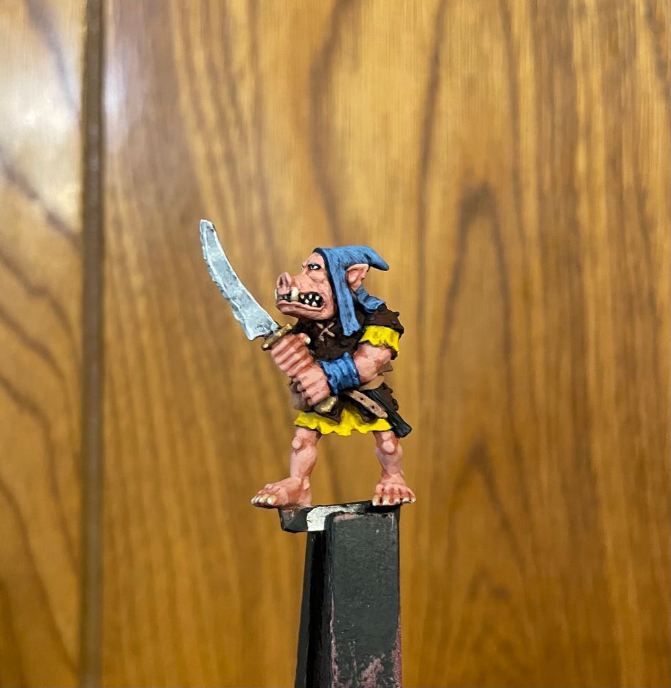 A 28mm pig faced orc miniature holding a two handed sword. It was sculpted by Kev Adams.