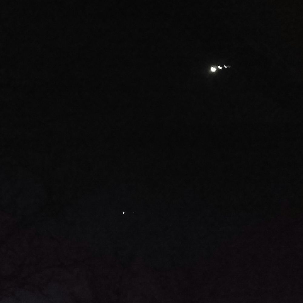 Cell phone photo of the night sky through a window pane. It probably shows the moon and Venus