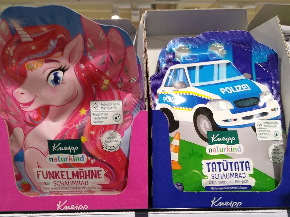 Zwei Sorten Schaumbad in Tüten von Kneipp im Regal. Fürchterliches Gendermarketing in pink und blau: links abgebildet ein pinkes Einhorn mit Flügeln und Glitzer und Sternen in der Mähne, Produktname "Funkelmähne" – rechts abgebildet ein Polizeiauto mit Blaulicht fährt auf einer Straße, am Straßenrand ein Verkehrskegel, Produktname "Tatütata"