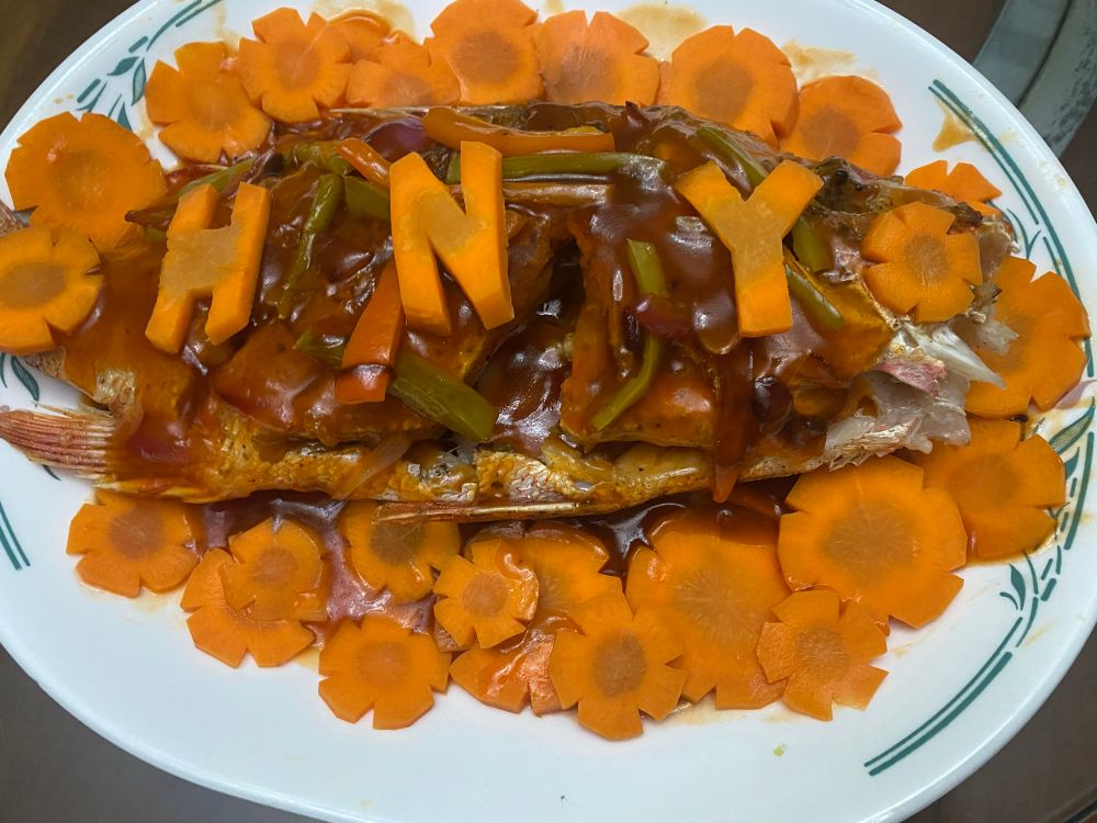 sweet and sour fish with carrots cut to spell out HNY
