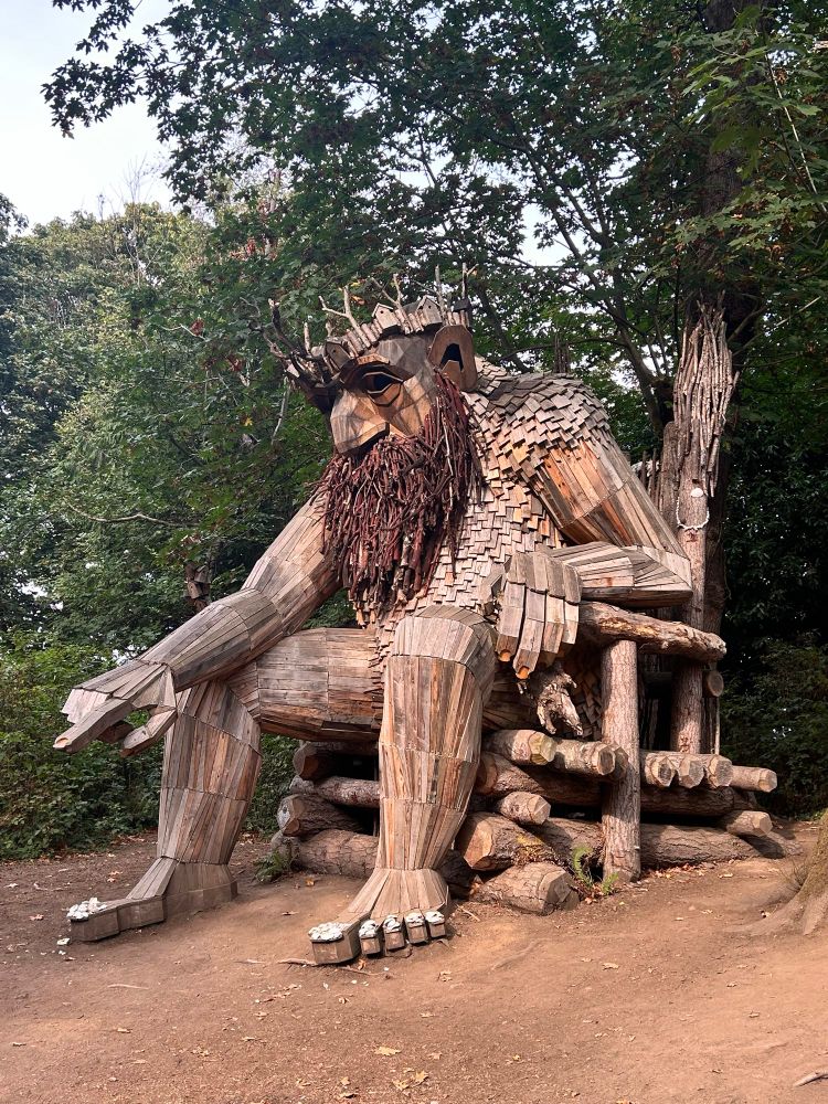 Zoomed out photo of Oscar the Bird King’s face. You can see the full troll statue in this photo he is sitting on a throne and pointing down at an angle. The statue and throne is placed in a clearing in the woods of a park on Vashon Island.
