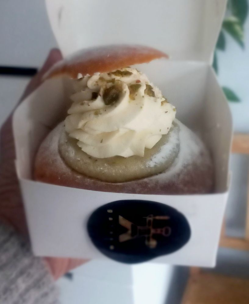 Laskiaispulla pistaasitäytteellä avatussa leivoslaatikossa