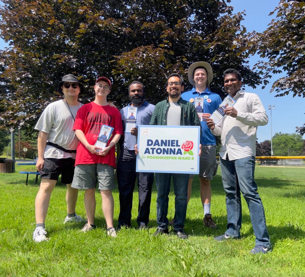 I’m in a group photo outside at Spratt Park with five of my supporters. We are about to canvass for my campaign so we have palm cards and a yard sign.