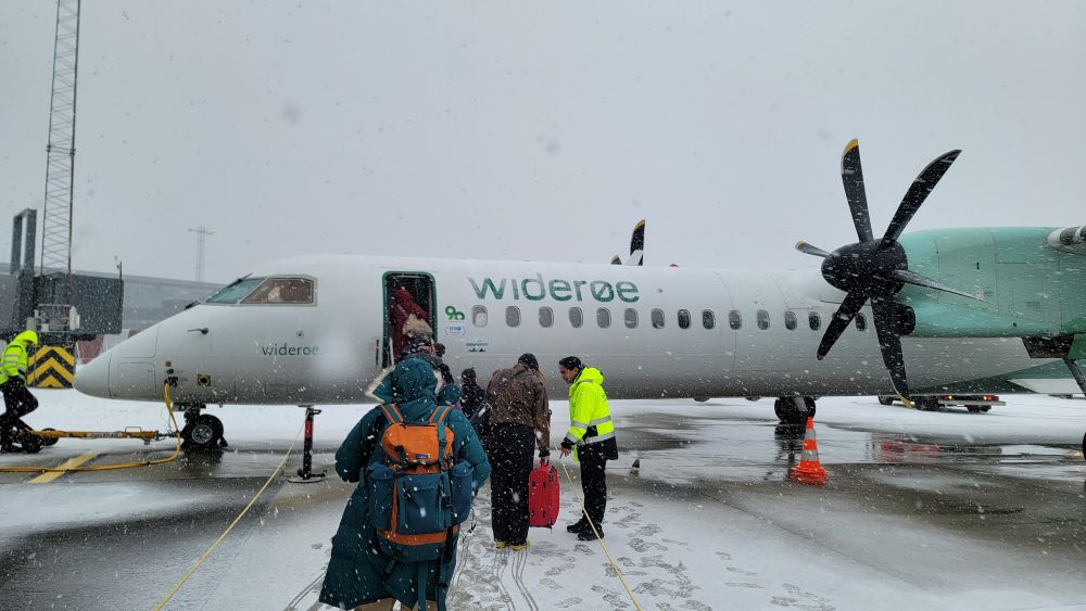 Passengers boarding a twin engine prop plane in snow 