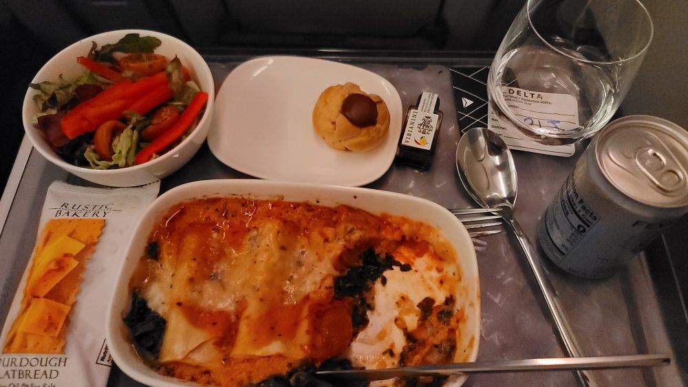My meal aboard my flight - a salad with red bell peppers, two pastries (one eaten), some flatbread, and a manicotti pasta dish.