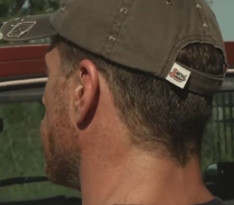 Closeup of a character wearing a hat with a prominent manufacturer's logo