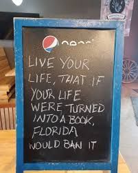 Ardoise affichée dans un restaurant avec écrit à la craie :

EN : Live your life, that if your life were turned into a book, florida would ban it

FR : Vis ta vie telle que si ta vie était transformée en livre, la Floride l'interdirait 