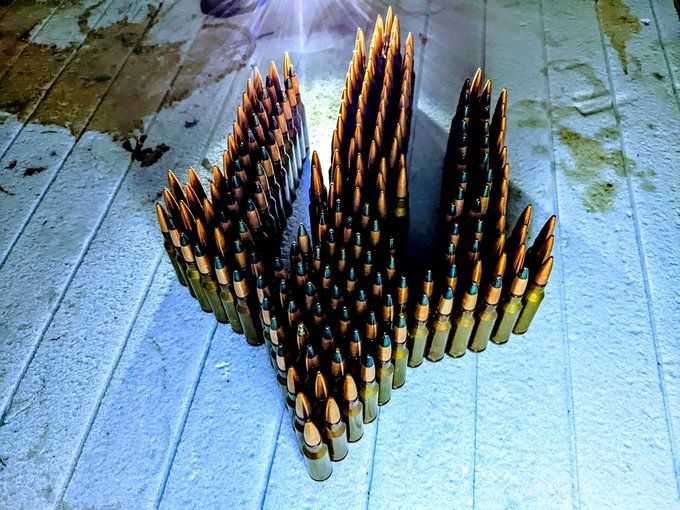 An Ukrainian tryzub made from big caliber rifle bullets. Shone with light on light blue floor planks. #Ukraine 