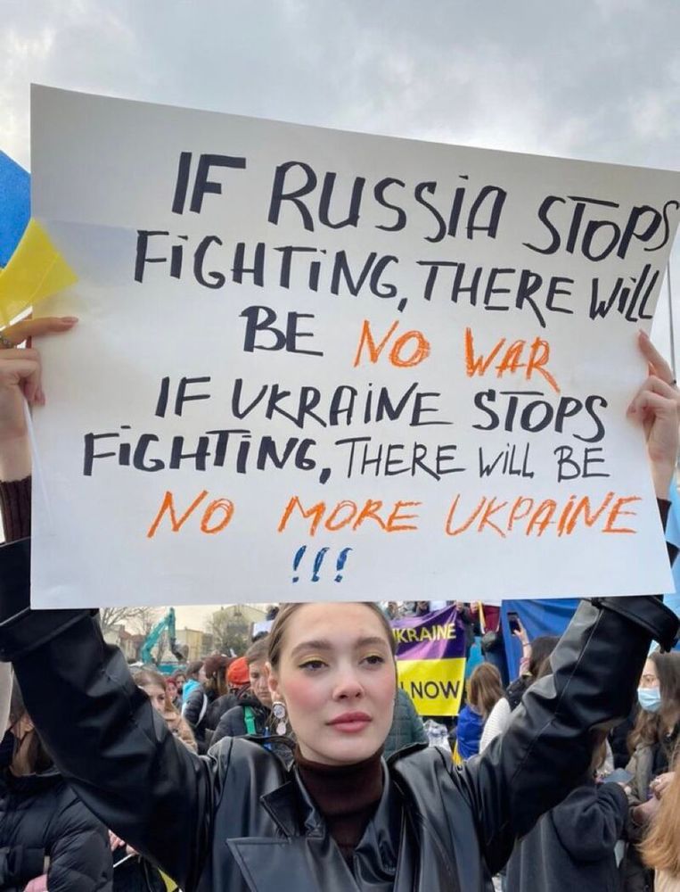 Young Ukrainian woman holds a rally sign above her head, on which is written: 