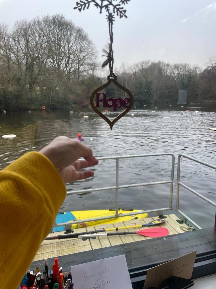Finger pointing at a “Hope” decoration with a pond in the background 