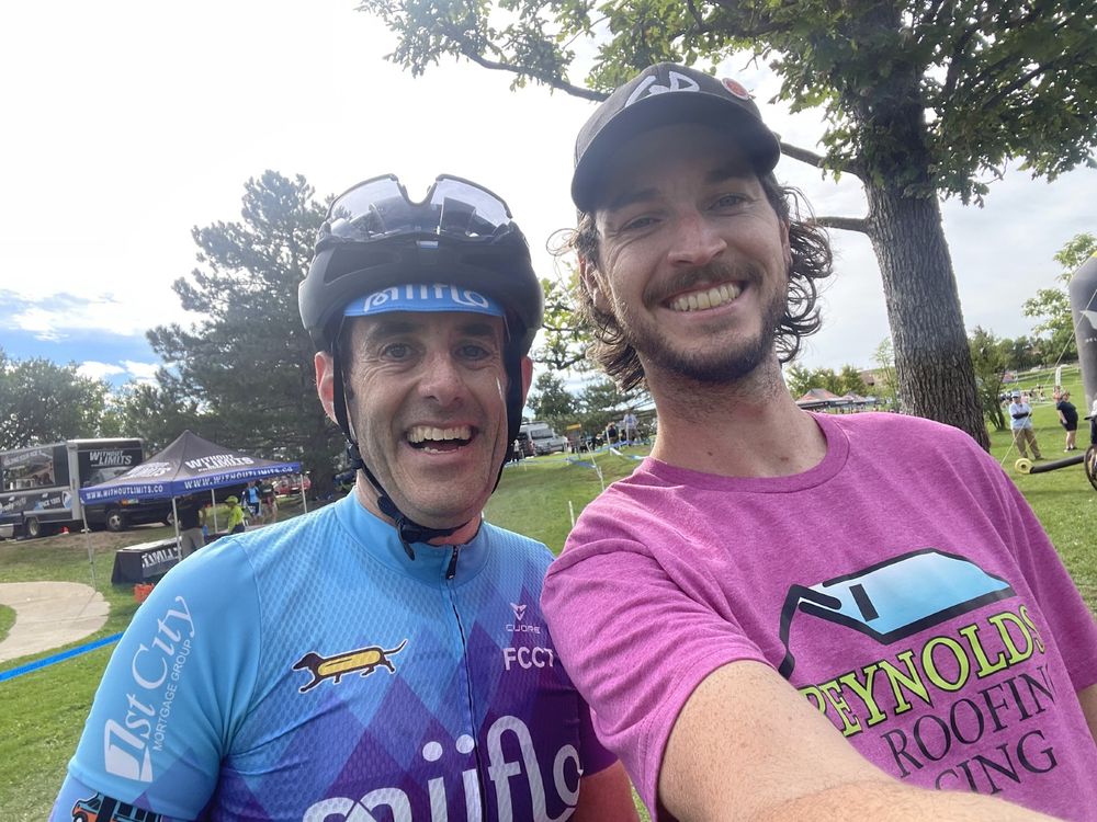 james smiling in bike kit, me smiling in post race tee shirt and hat