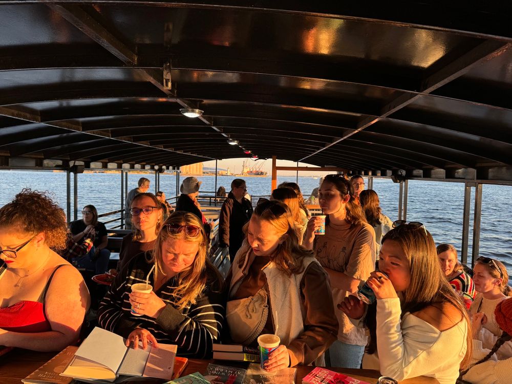 Passengers on the greedy reads sunset cruise and book swap checking out the table of books to choose from 