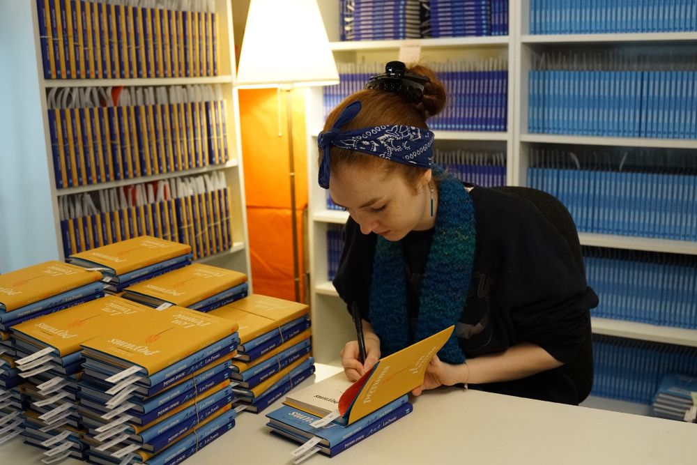 Photo of Len Pennie signing copies of yellow, light blue and dark blue books