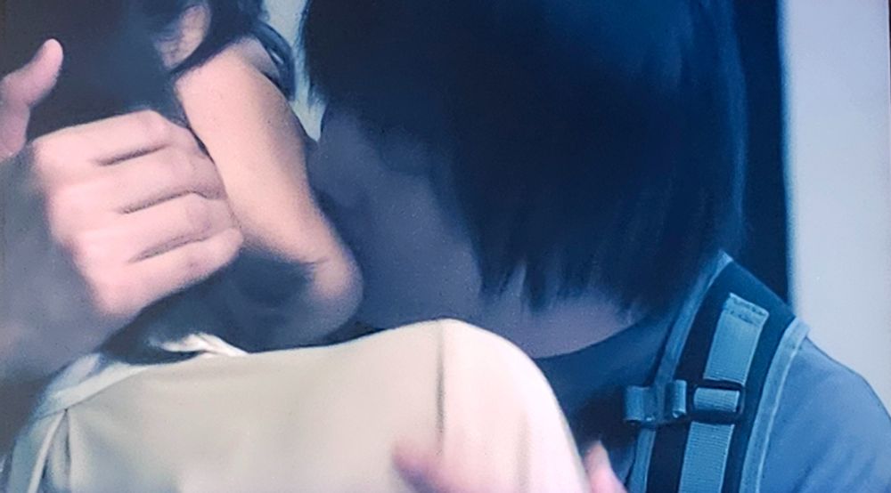 Kagiya Senri kisses Kosaka Maiko as he holds her head gently in his hand. His other hand grasps her upper arm to bring her closer. He wears a backpack as they've just stepped inside her door. This if from the jdrama Ripe For The Picking.