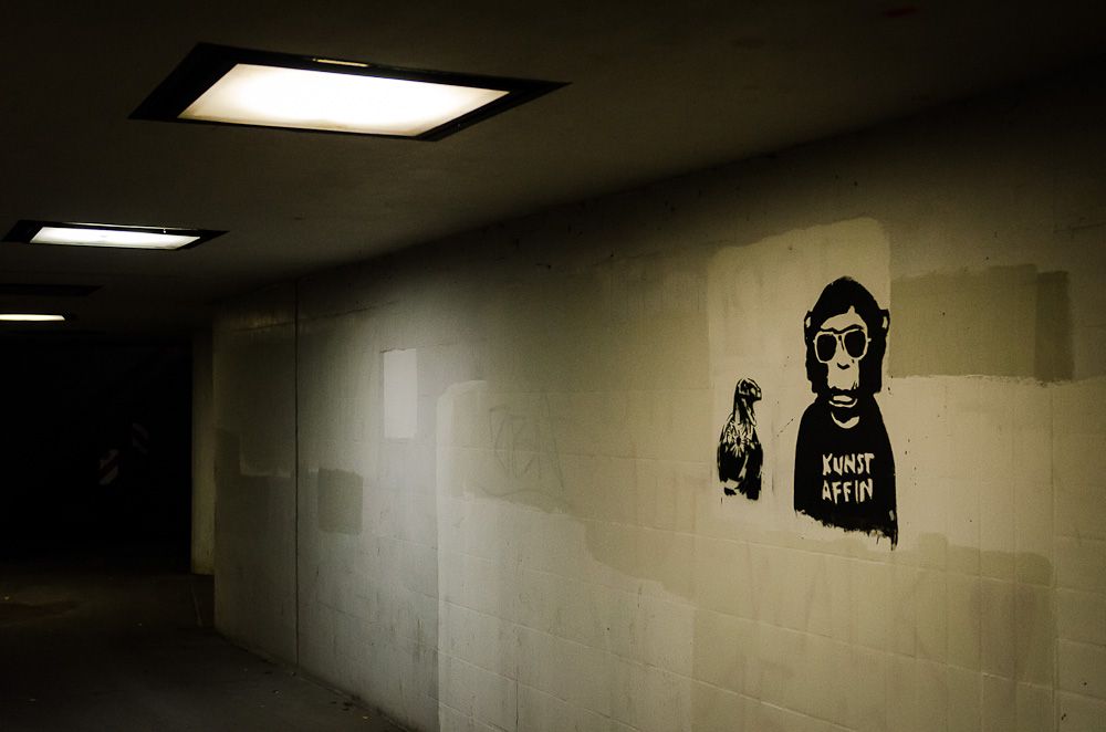 An artistic stenciling of a monkey wearing sunglasses with the words Kunst Affin on its chest. 