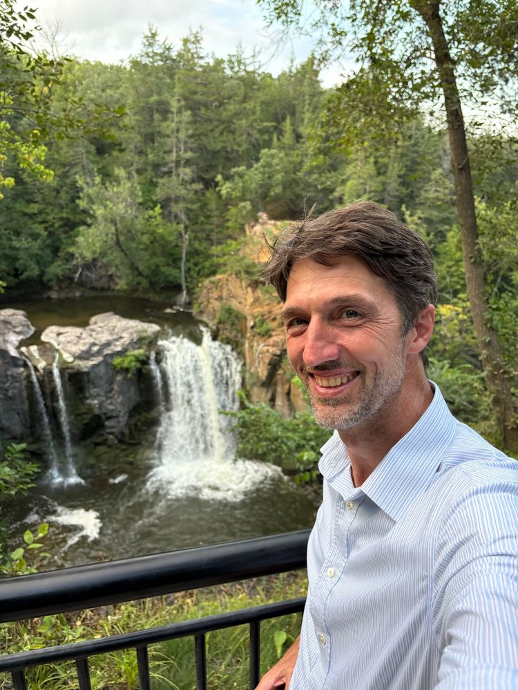 Doron standing in front of a waterfall