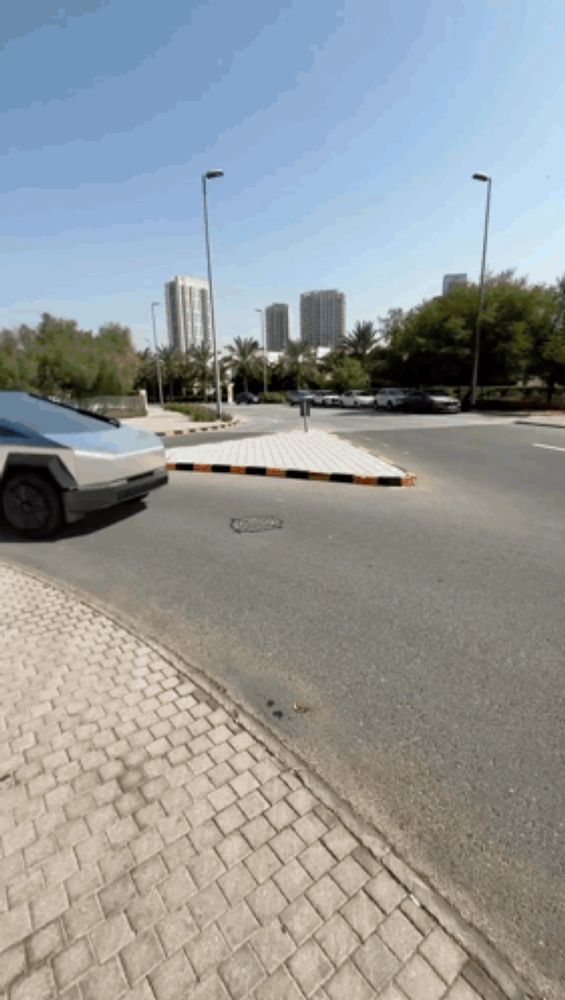 a car is driving down a street with a brick curb