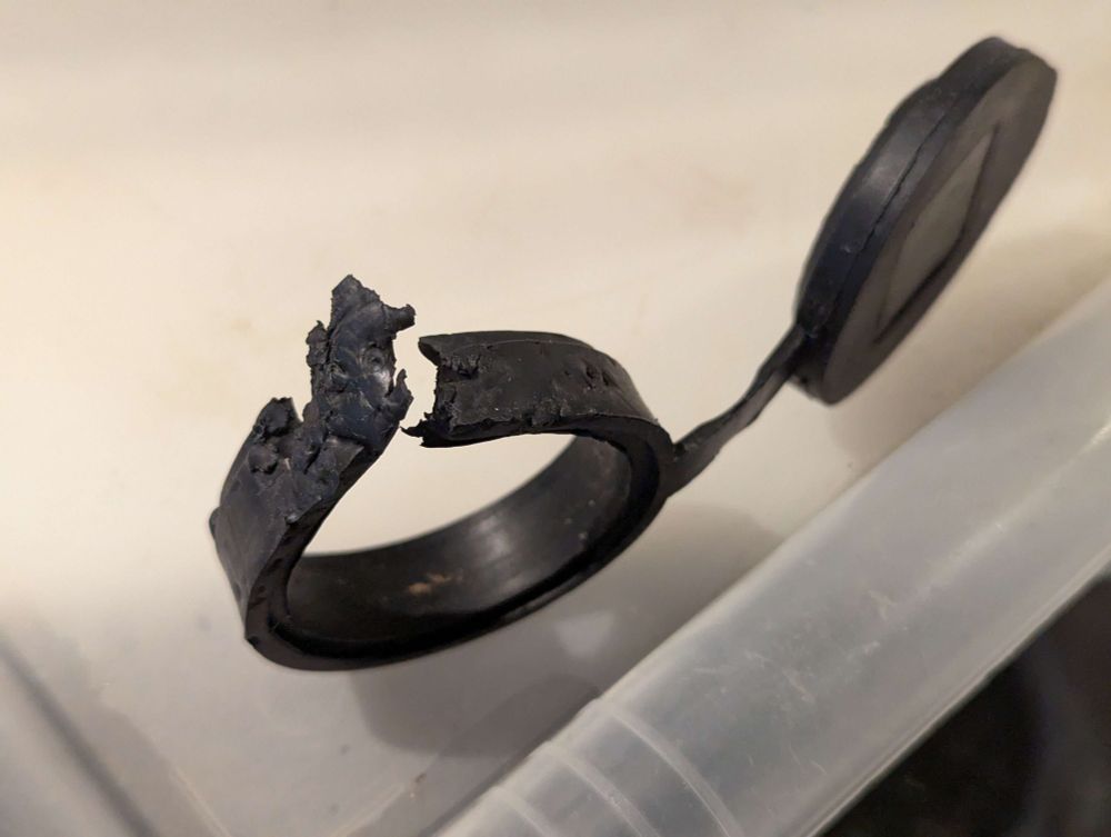 un anneau plat en plastique relié à un bouchon. l'anneau est cassé ouvert, clairement à force d'avoir été mordillé avec enthousiasme et néanmoins des dents bien pointues.