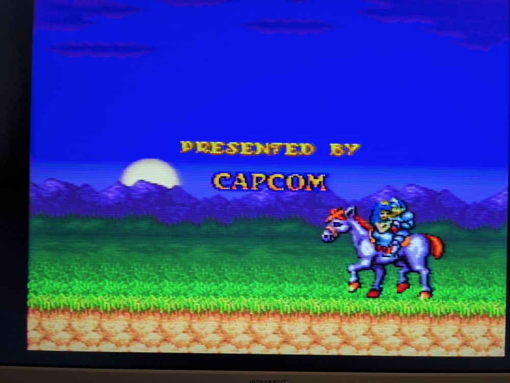 A screenshot of the ending to Chou Makaimura. Arthur and Princess Prin Prin are riding a white horse, while the words "Presented by Capcom" float overhead.