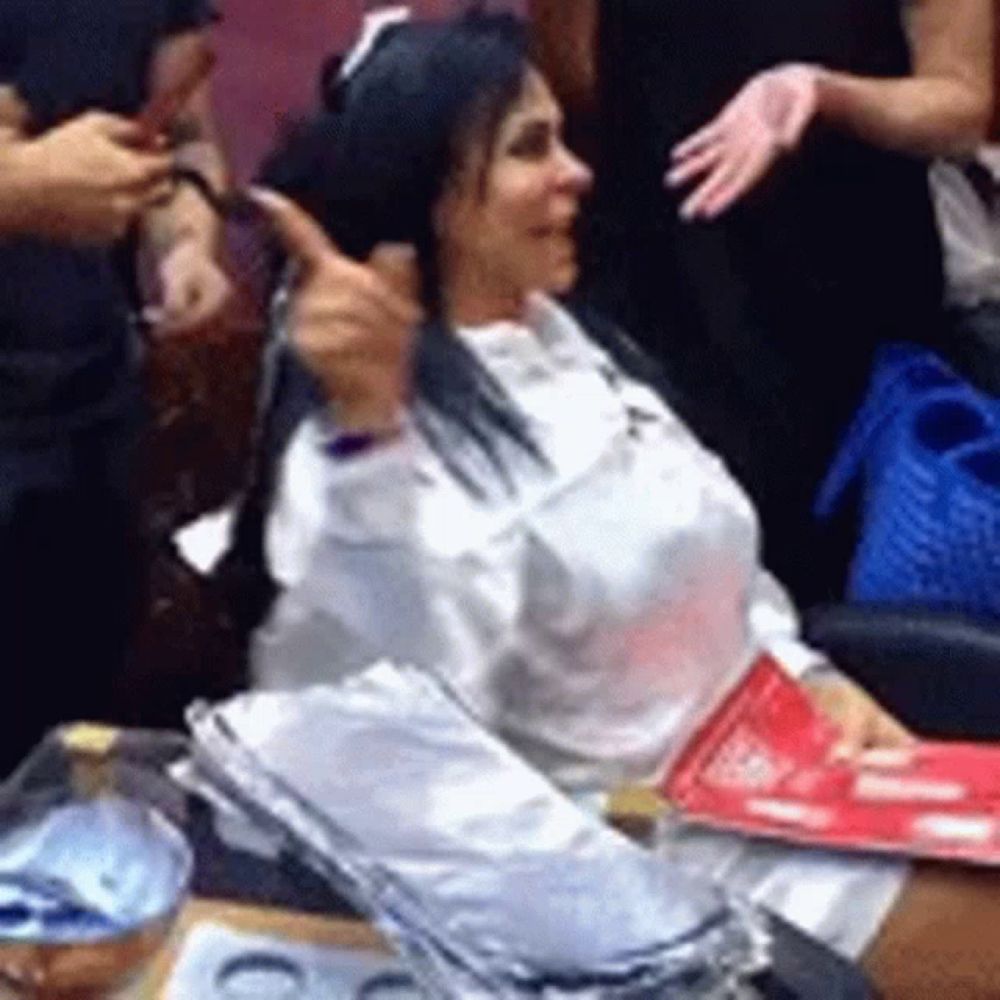 a woman is getting her hair dyed and giving a thumbs up