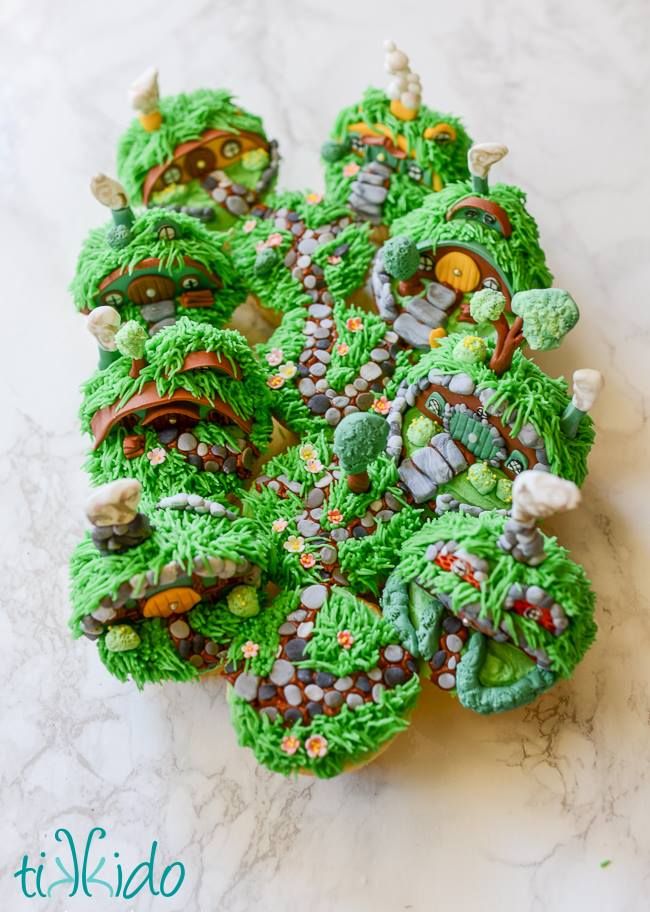 12 cupcakes decorated to look like Hobbit homes and garden paths, all clustered together to look like the Shire.
