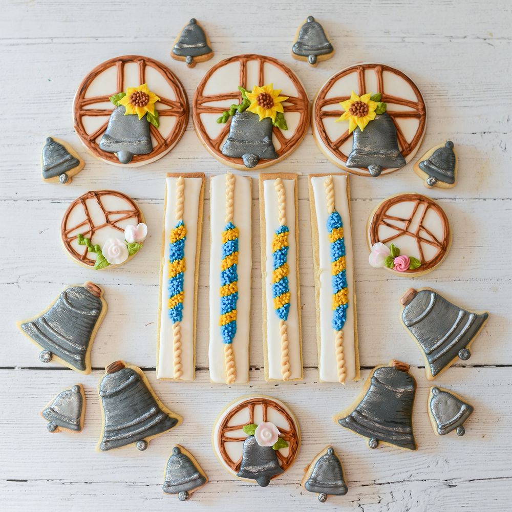 Set of sugar cookies decorated with royal icing with an English change ringing (bell ringing) theme.  22 cookies that look like bells, bells on bell wheels, and fluffy sallys striped blue and gold for the St Albans colors.