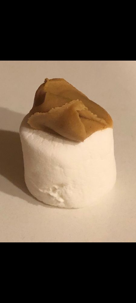 A single marshmallow topped with a dollop of peanut butter.