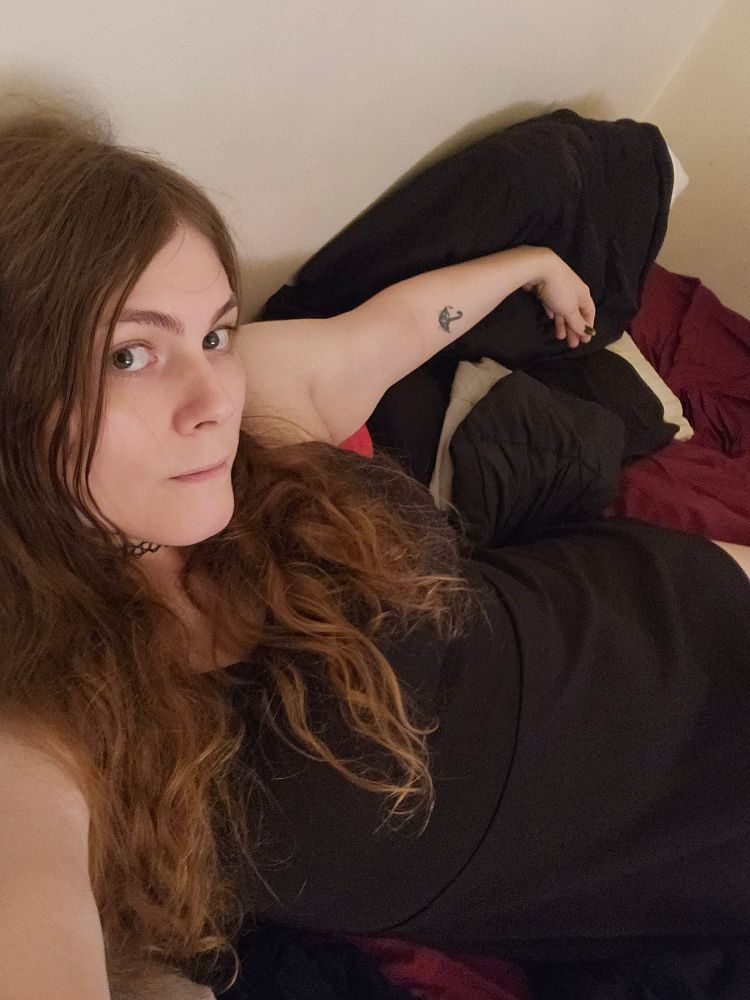high angle selfie of me splayed on the bed wearing a black dress and black tattoo choker