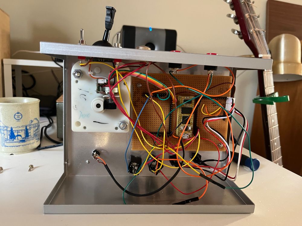 The inside of a prototype electronic musical instrument, showing wires, a Daisy Seed microcontroller, and a string controller