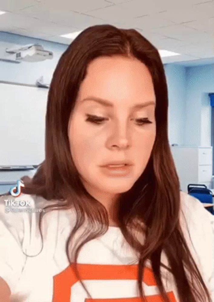 a woman with long brown hair is wearing a white and orange striped shirt in a classroom .