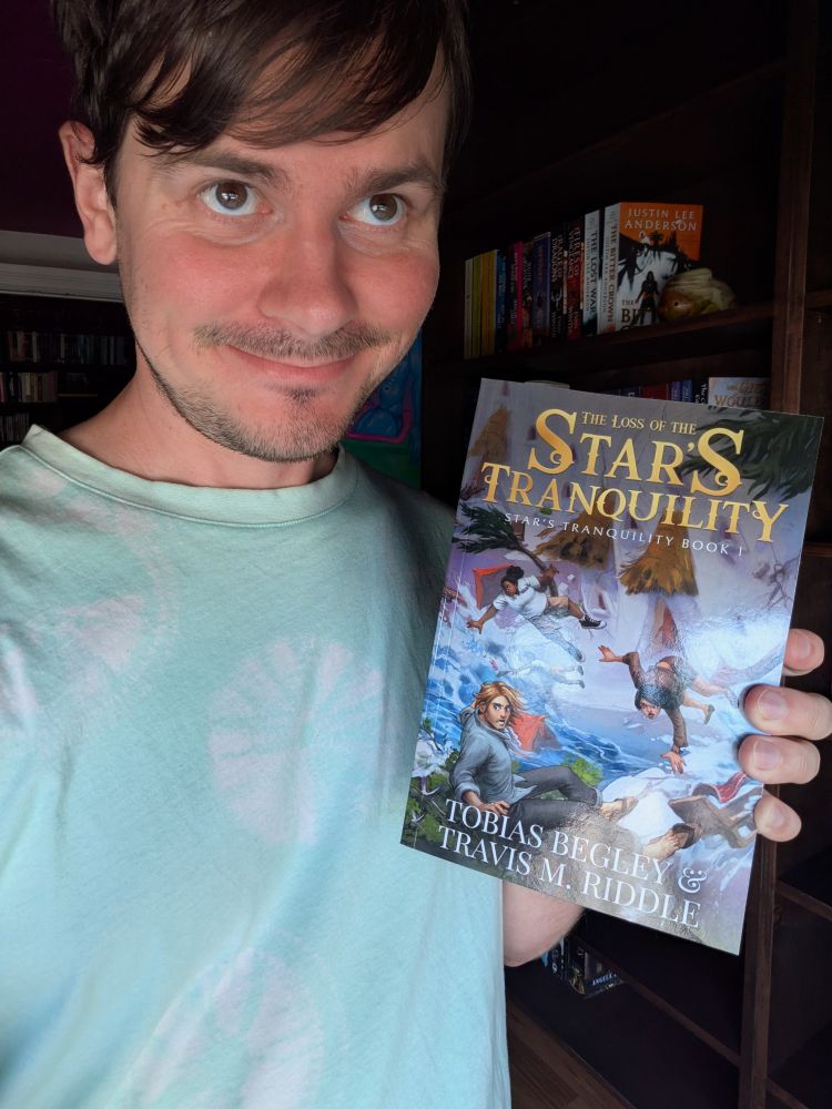 Caucasian male holding a paperback copy of the fantasy novel The Loss of the Star's Tranquility 