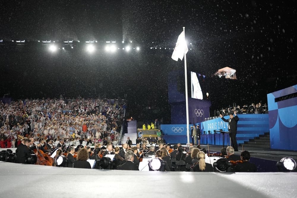 L'Orchestre National de France, le Chœur de Radio France et le chef Christian Măcelaru sous la pluie au Trocadéro pendant la cérémonie d'ouverture des JO de Paris 2024
