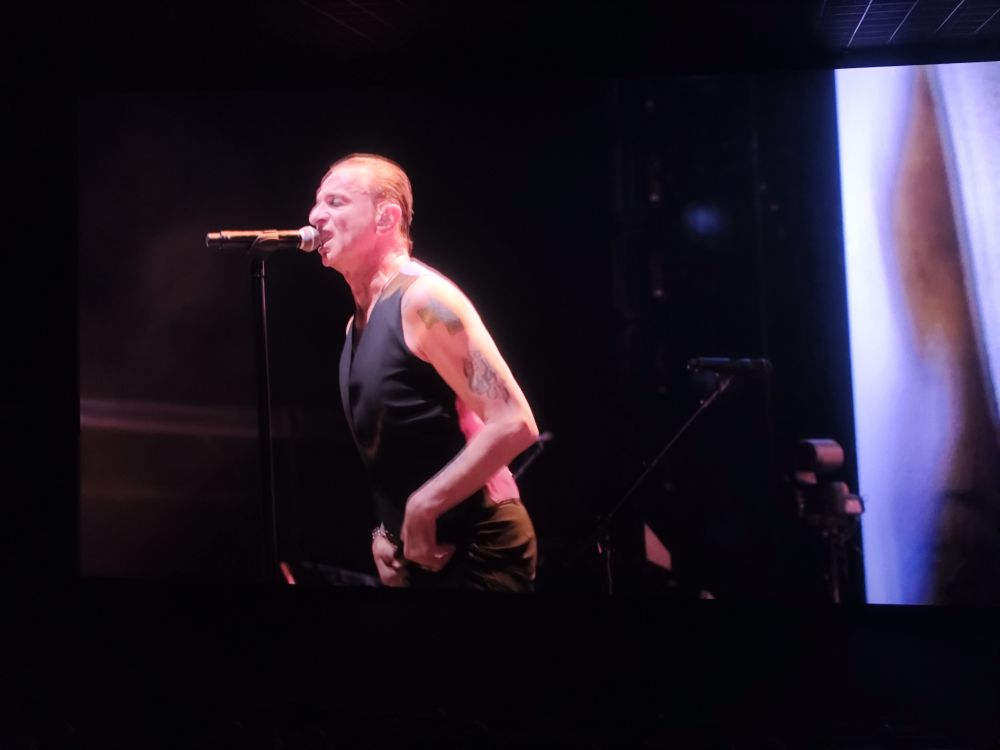 Dave Gahan , la voix de Dépêche Mode en gilet noir, le bras tatoué au micro.